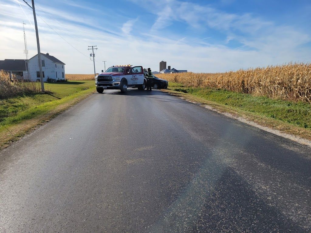 A white truck is parked on the side of a road next to a corn field.