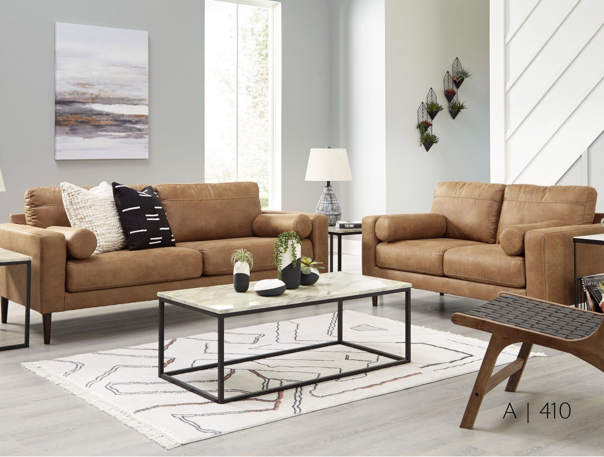 tan sofas, coffee table, rug, artwork, and modern chair.