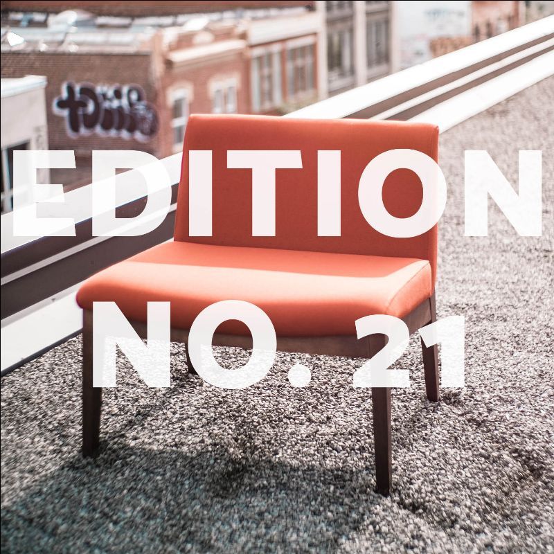Orange chair on a rooftop with graffiti and city buildings.