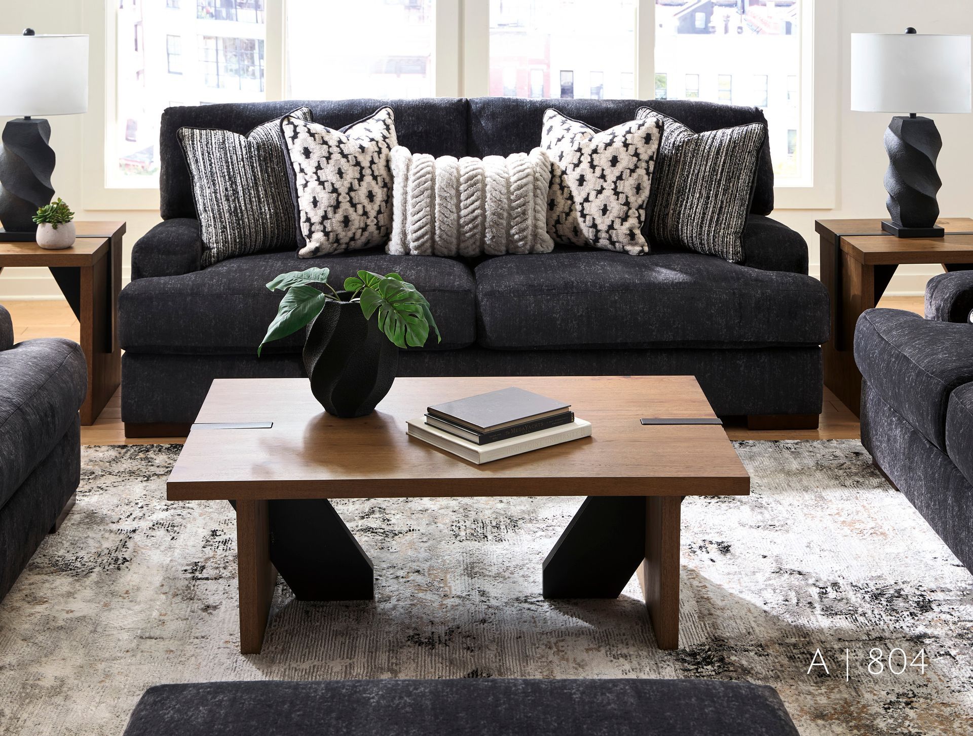 dark gray sofa, patterned pillows, wooden coffee table, and lamps.