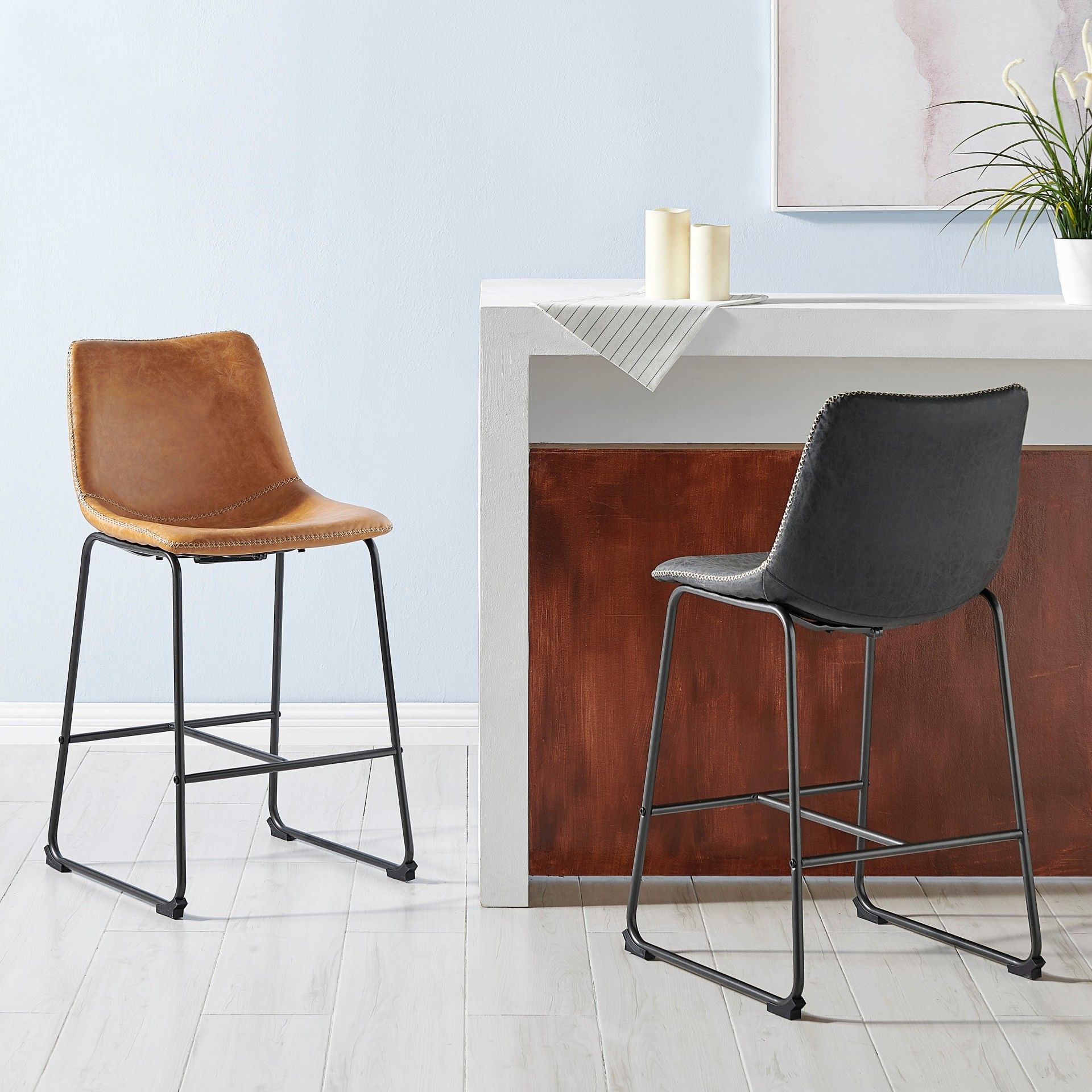 Two brown and black bar stools by a white counter.