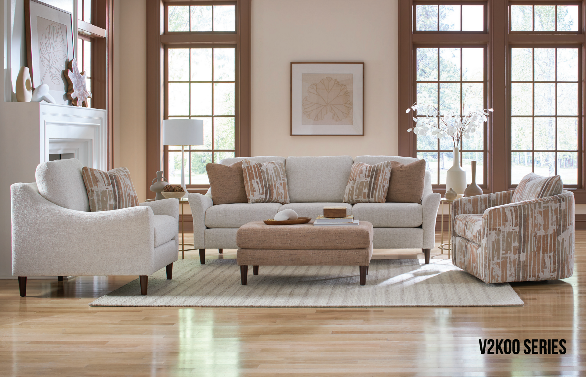 Living room set with a sofa, two chairs, and a matching ottoman on a rug, near windows.