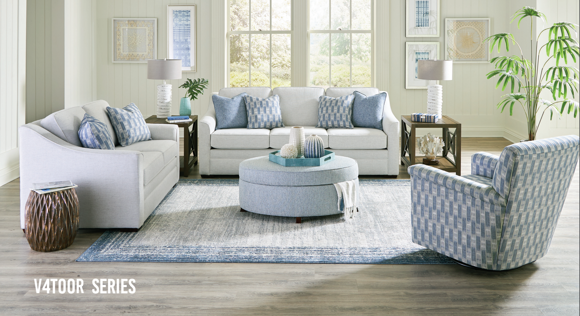 Living room with white sofas, blue accents, light wood furniture, and a rug.