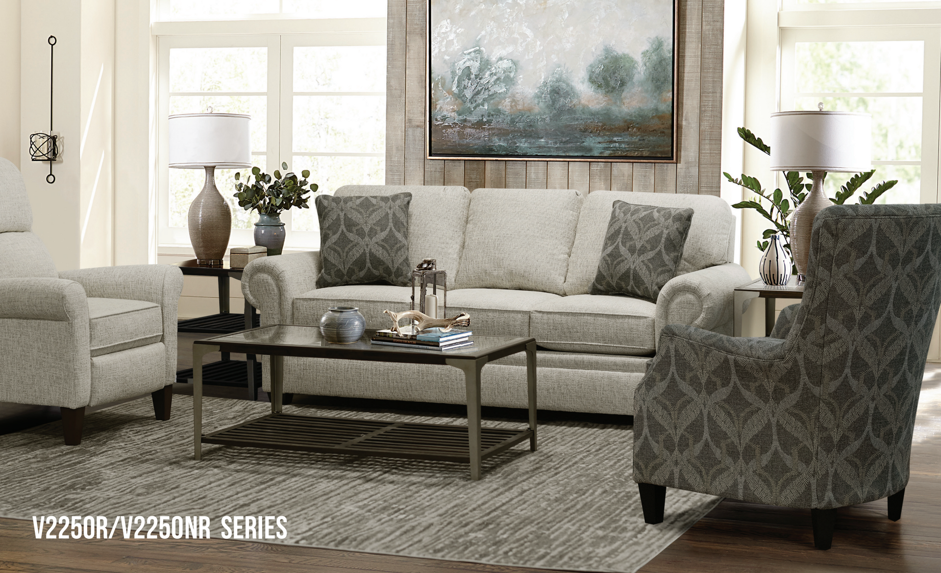 Living room with couch, armchairs, coffee table, rug, and artwork.