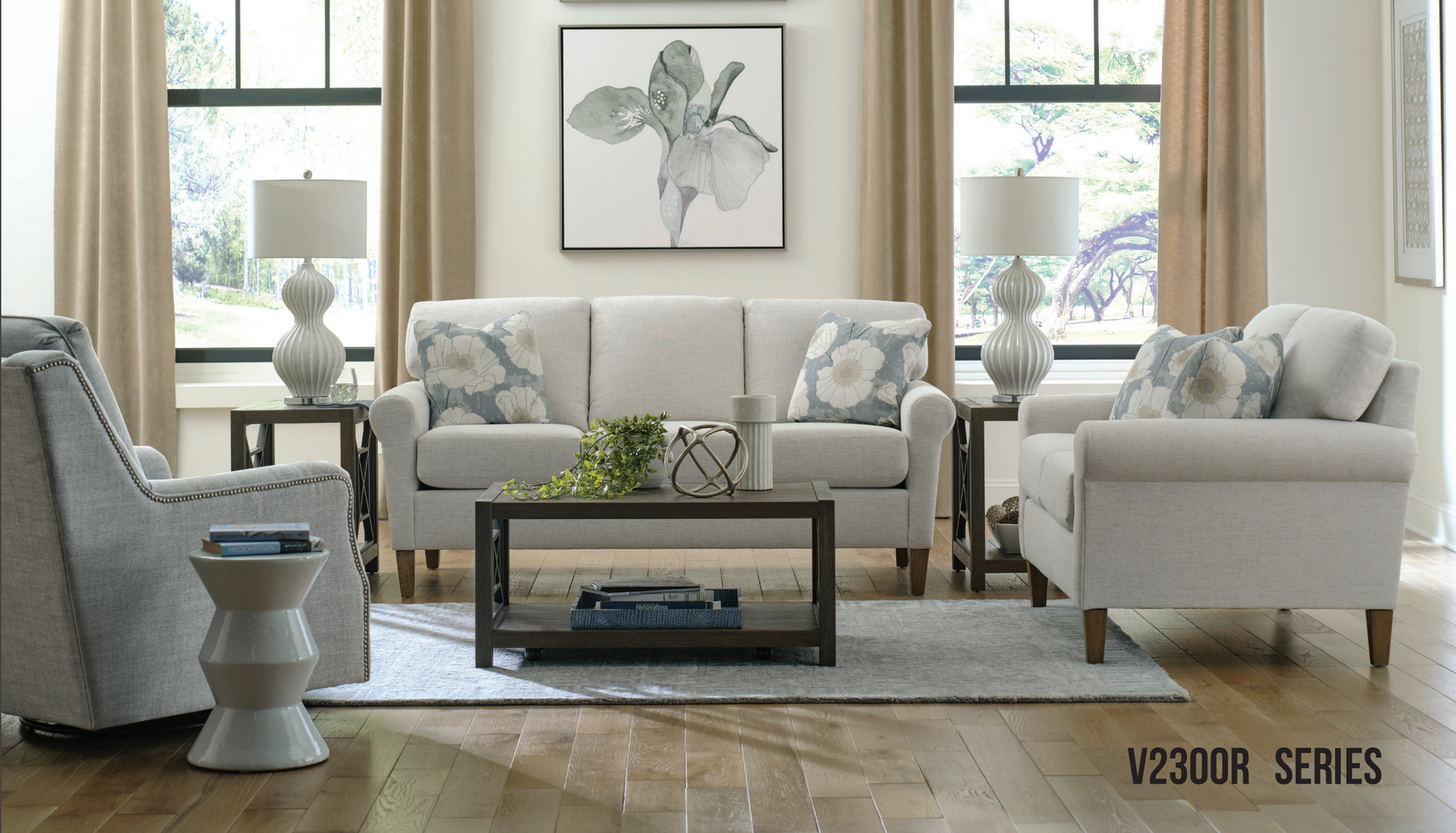 Living room furniture set with a sofa, chair, and accent table. Neutral colors with floral pillows and artwork.
