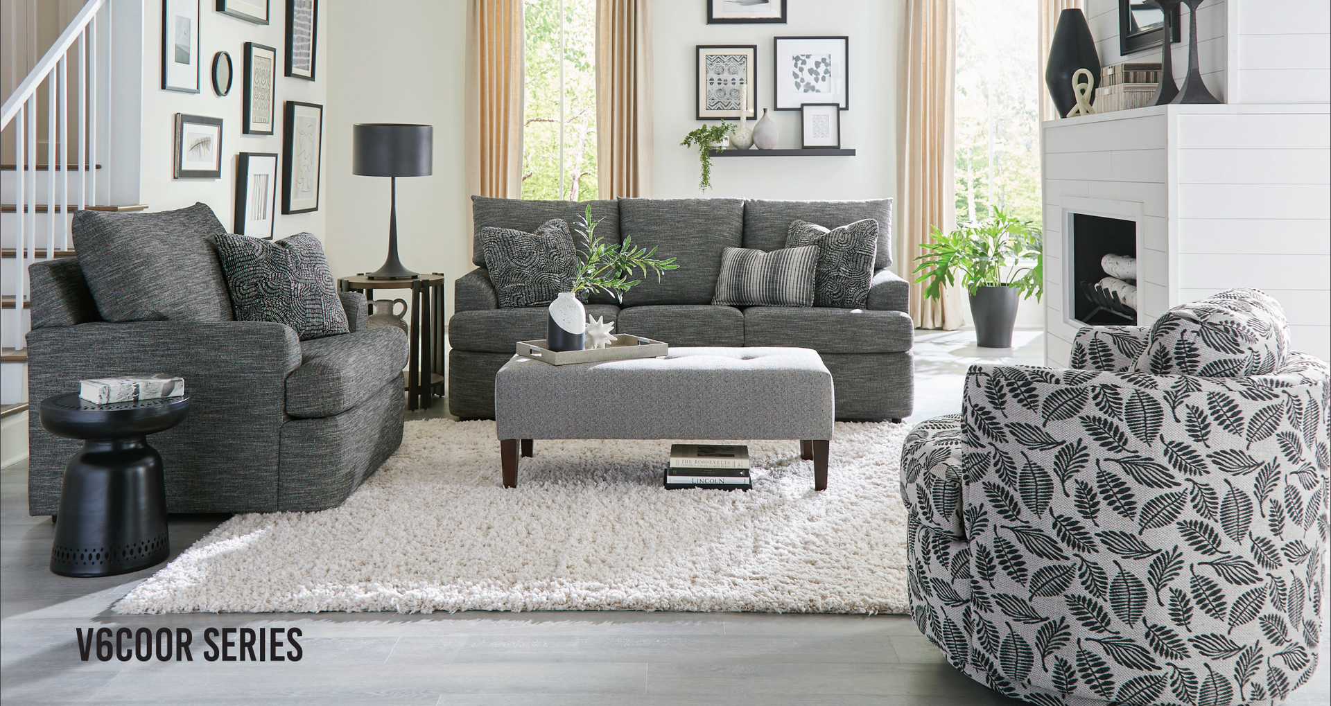 Living room with a gray sofa, chair, ottoman, and rug. Various framed artwork on walls.