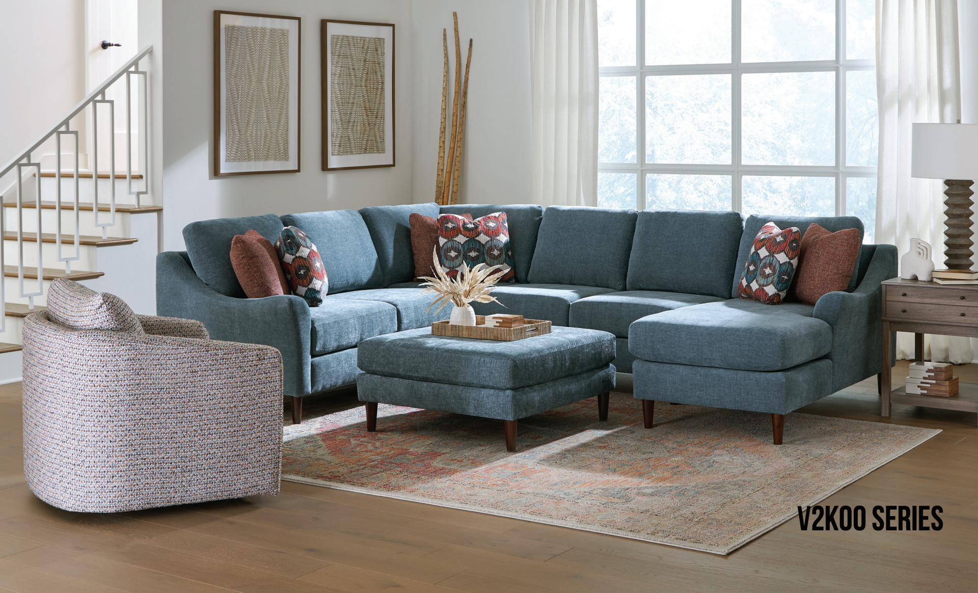 Blue sectional sofa with ottoman in a living room, next to a patterned chair.