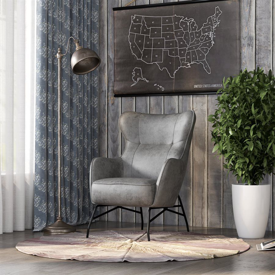Grey armchair in a room with a floor lamp, map, and houseplant on a round rug. Frankie Chair