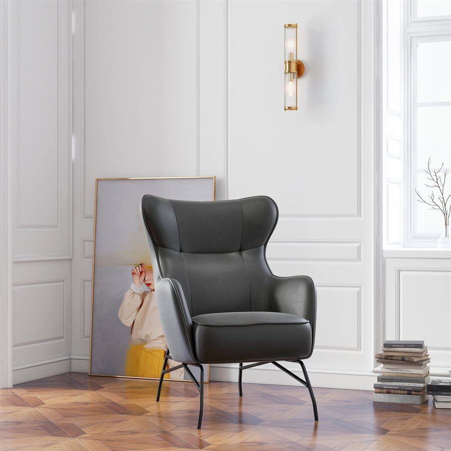 Gray leather armchair in a room with a painting, wall sconce, and stacked books.