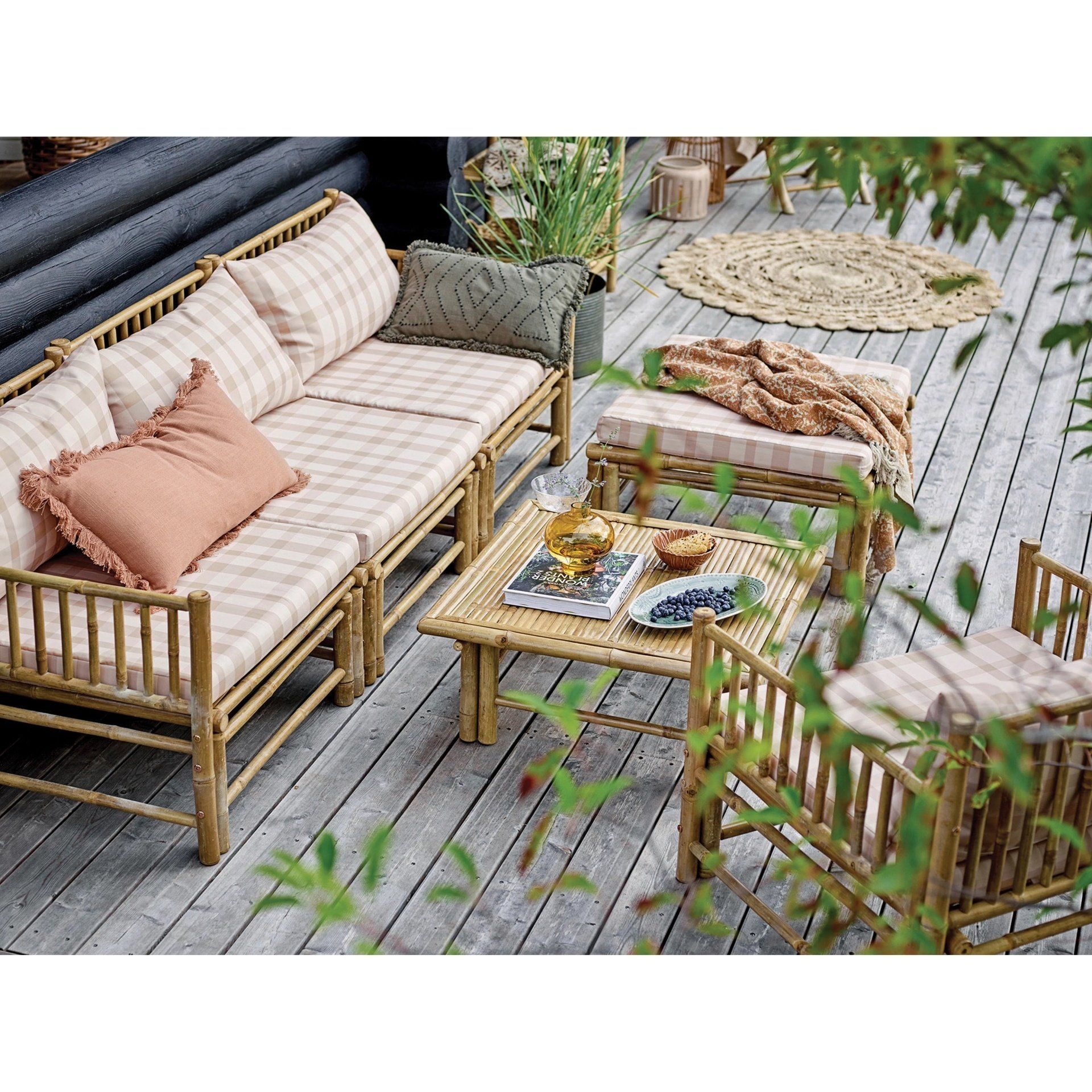 Bamboo patio furniture with checkered cushions on a wooden deck.