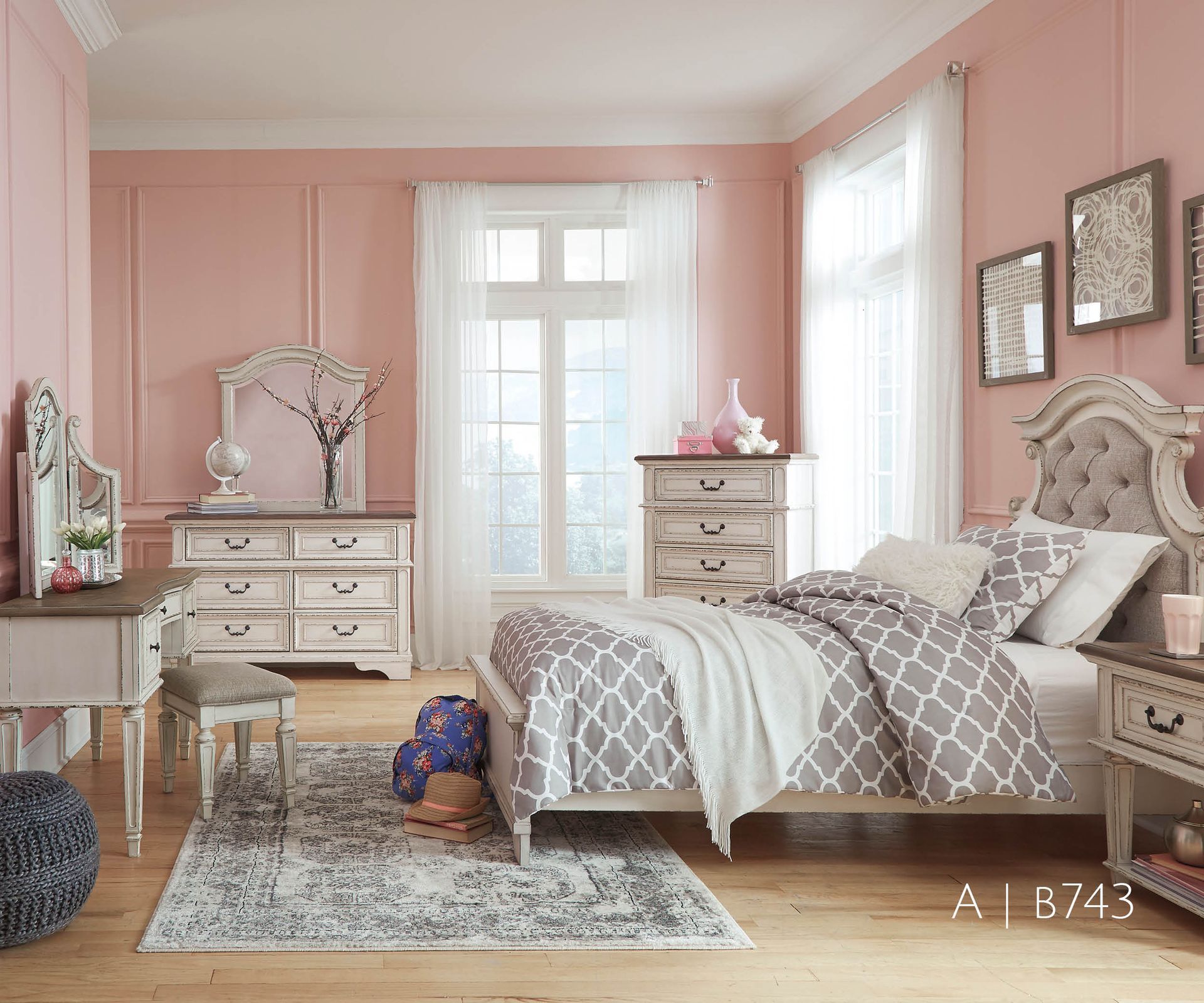 Bedroom with pink walls, white furniture, gray patterned bedding, and a window.