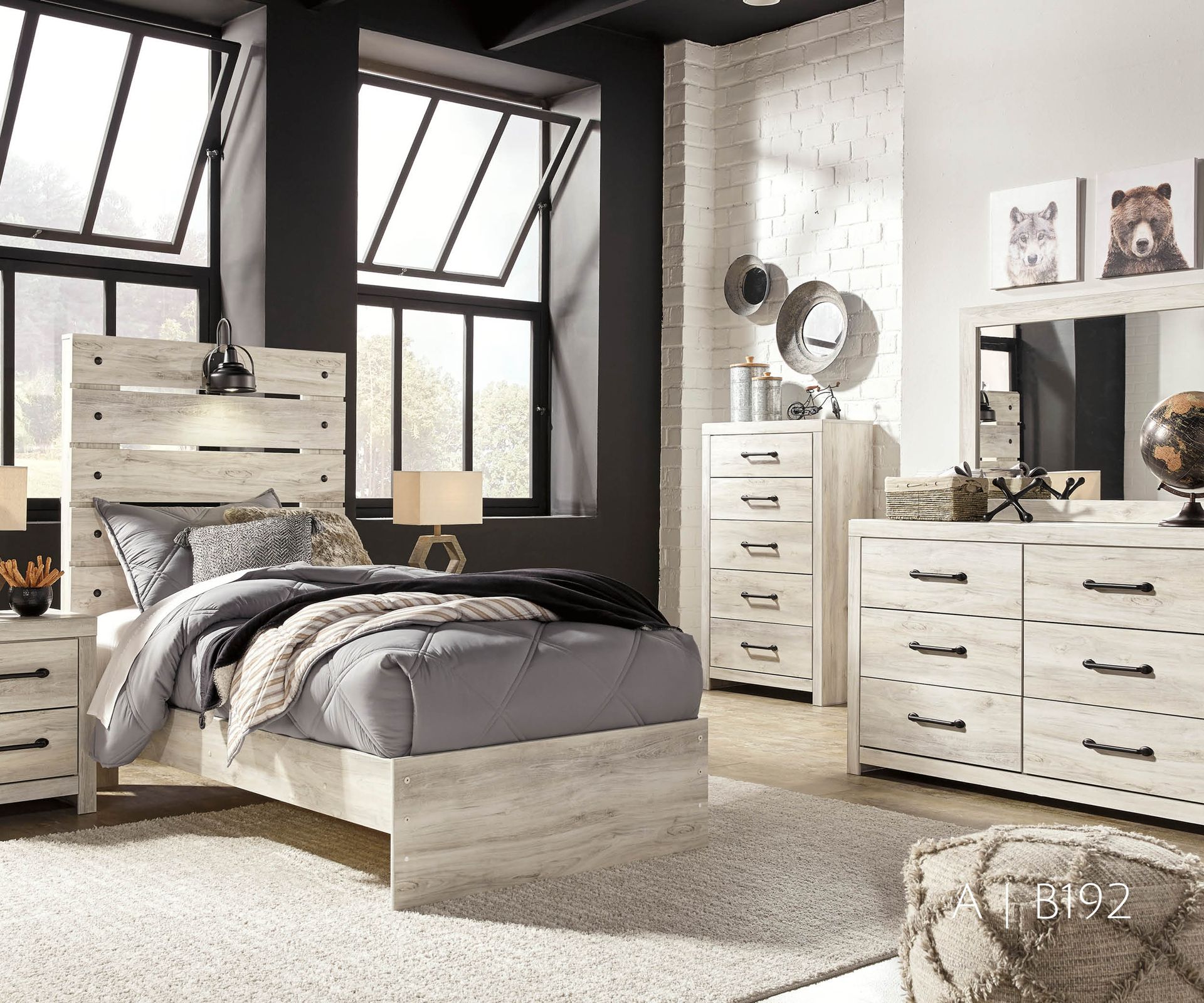 Bedroom furniture set with a bed, dresser, and chest in light wood against a dark wall.
