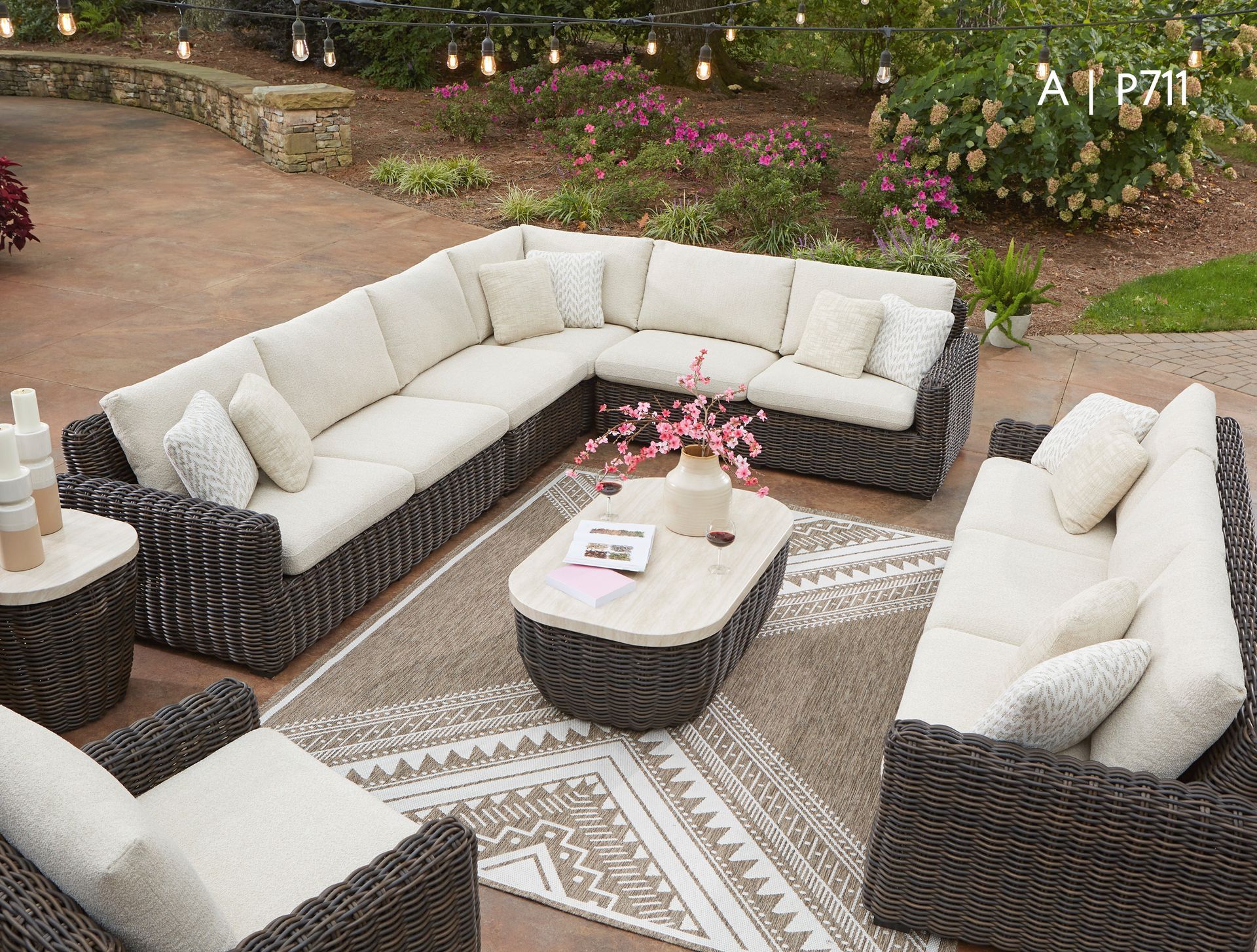 Outdoor sectional sofa with beige cushions, coffee table, and area rug.