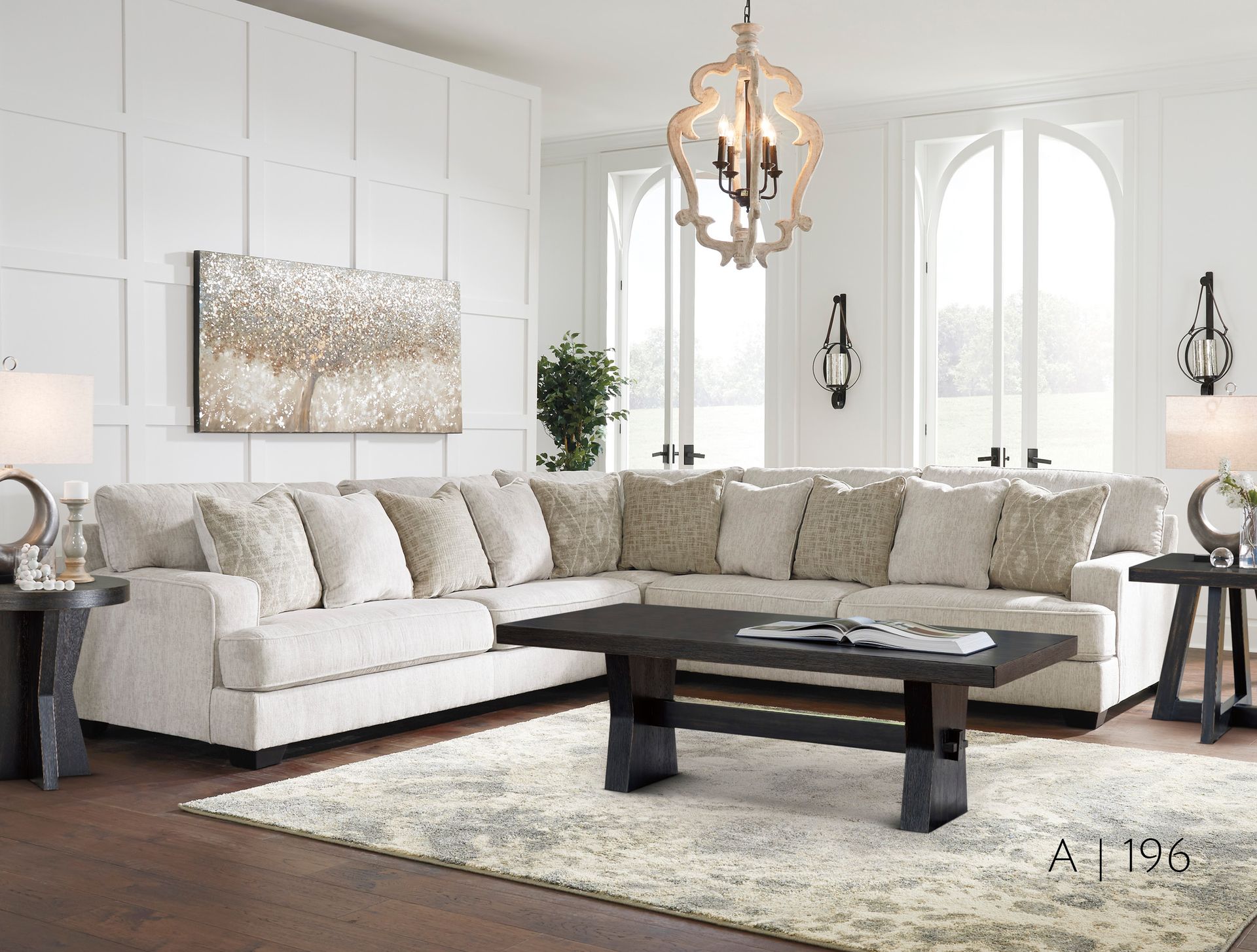 Cream-colored sectional sofa in a bright living room, with a rug, coffee table, and large windows.