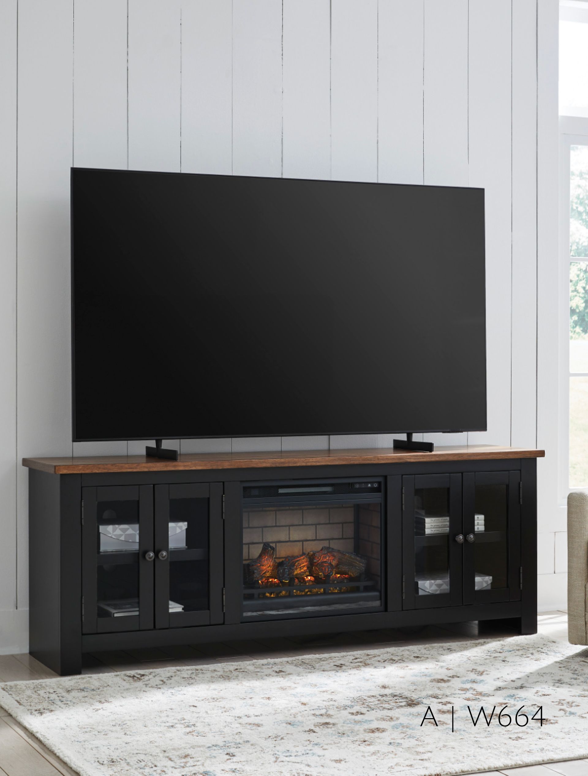 Black TV stand with electric fireplace, brown top, and a large black TV.
