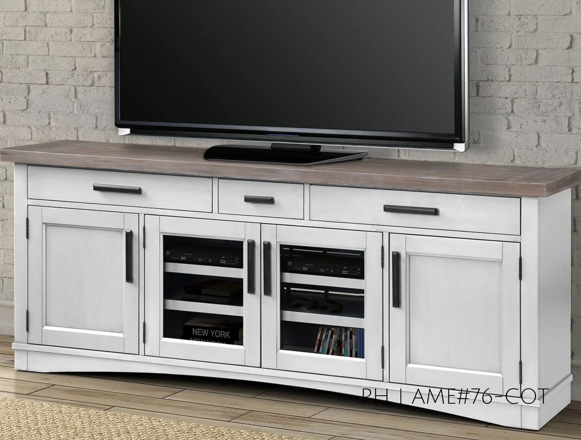 White TV stand with gray top, holding a black television against a brick wall.