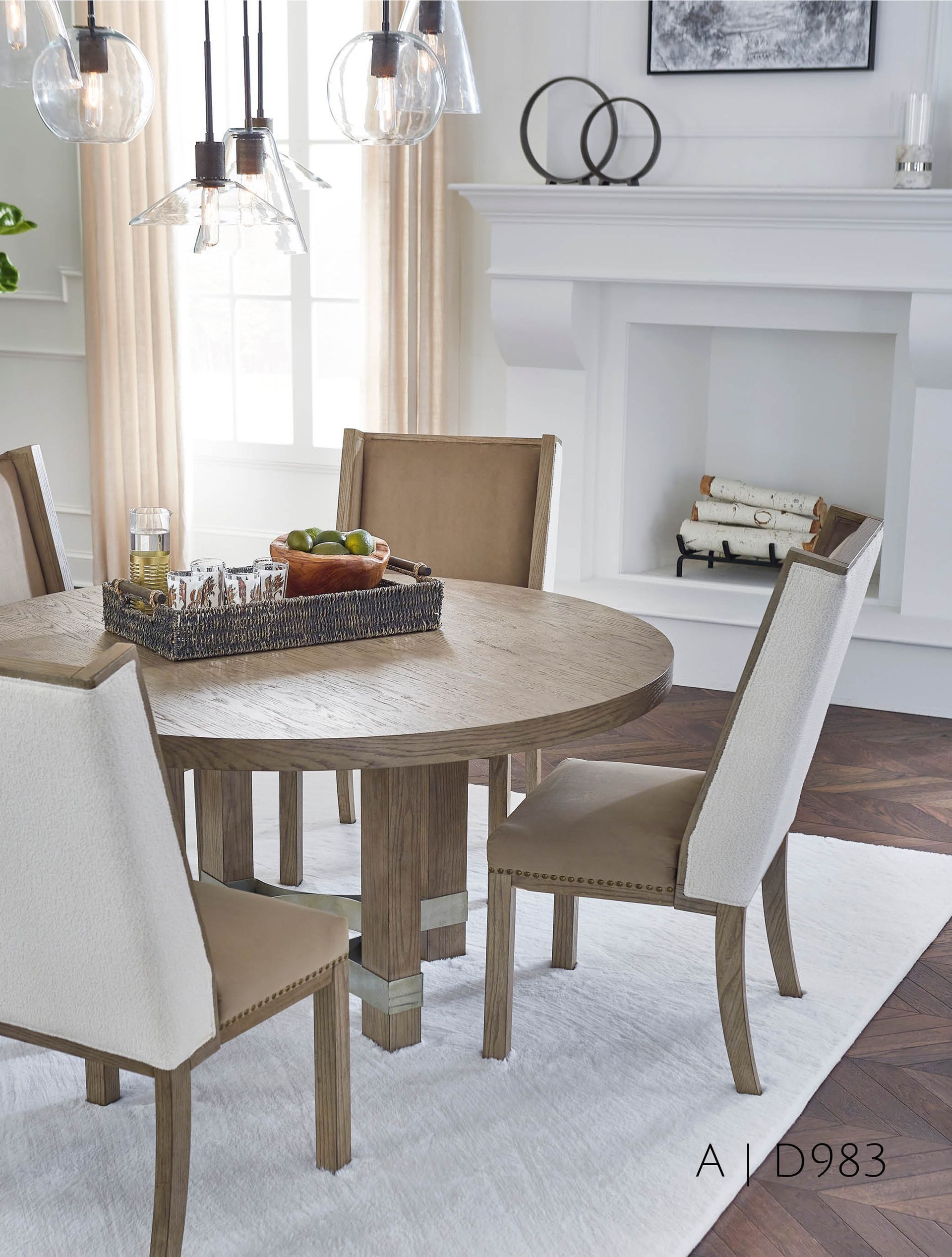 Round wooden dining table with four upholstered chairs in a neutral-toned dining room.