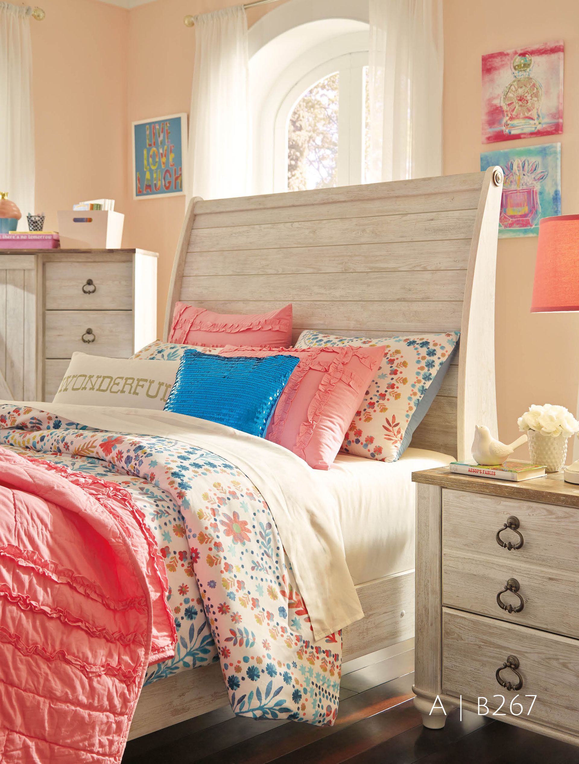Bedroom with a white distressed wood bed and nightstand; pink, blue, and floral bedding.