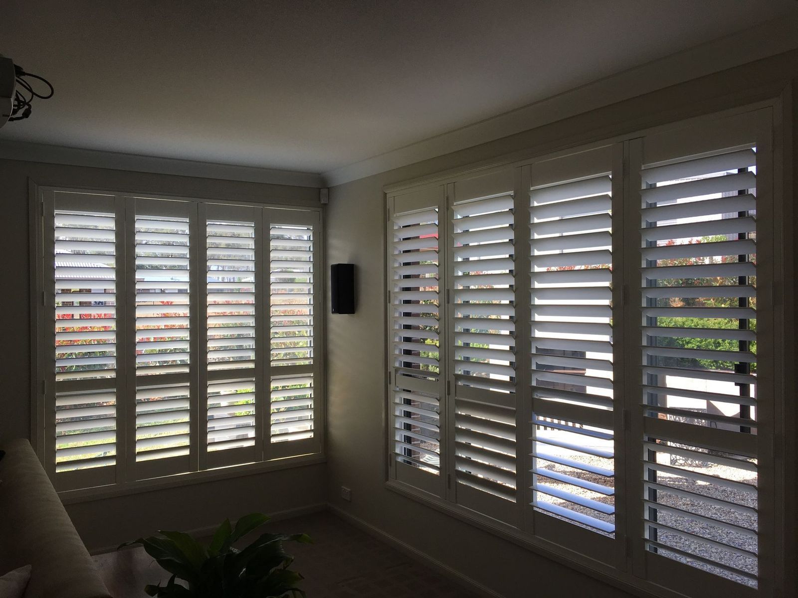 White shuttered windows in a room, angled sunlight.