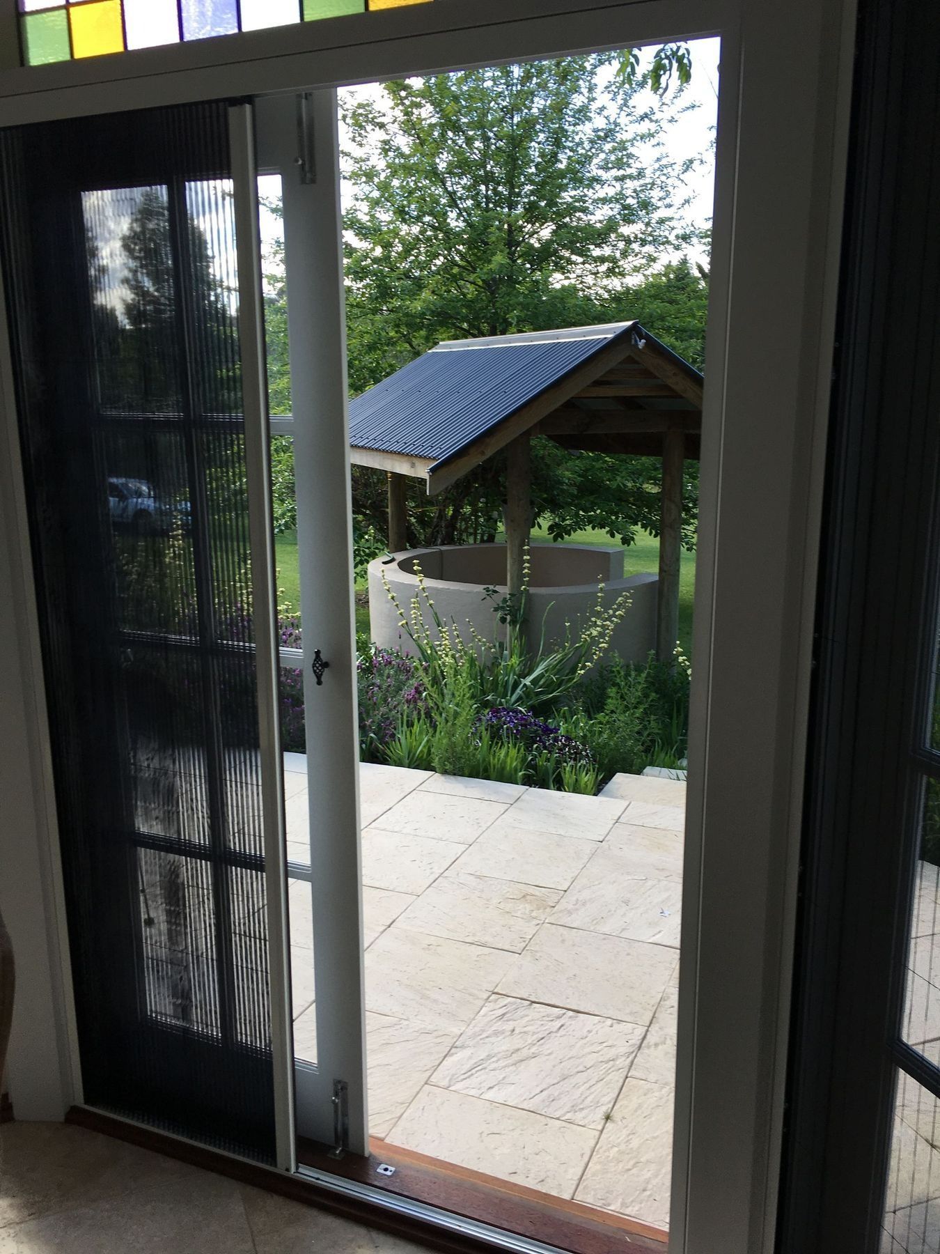 Open door to outdoor well with roof, surrounded by garden.