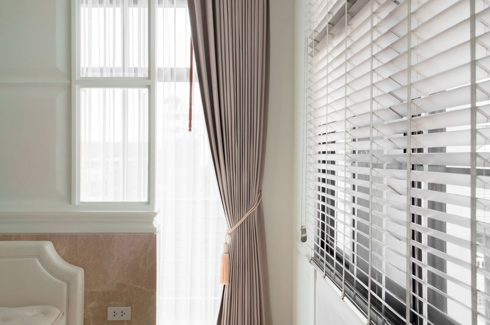 Interior with window, curtains, and blinds; cream walls; sunlight.