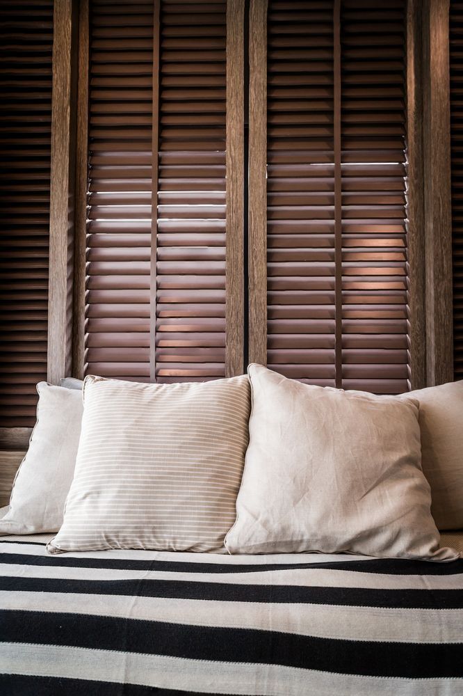 Beige pillows on striped seating against brown shuttered background.