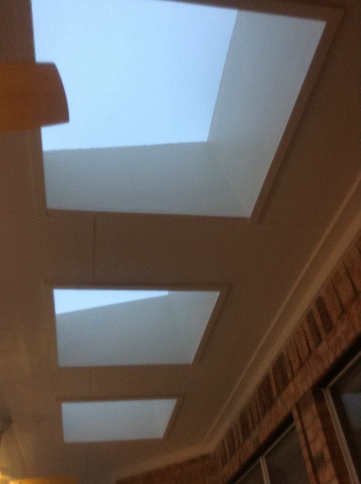 Three rectangular skylights in a ceiling, brick wall to the right.