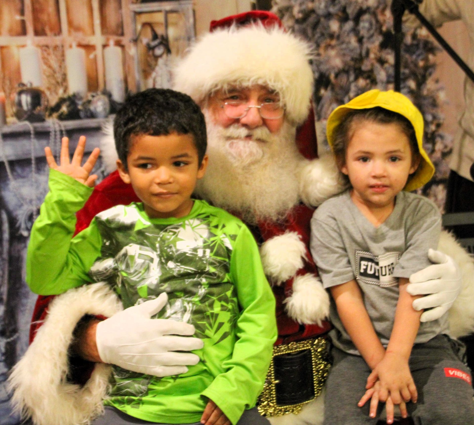 Two children are posing for a picture with santa claus