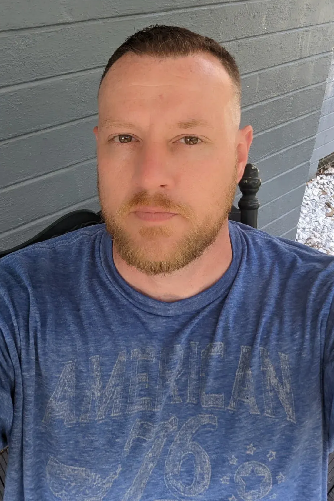 white man with brown hair and short beard facing camera in a blue tshirt