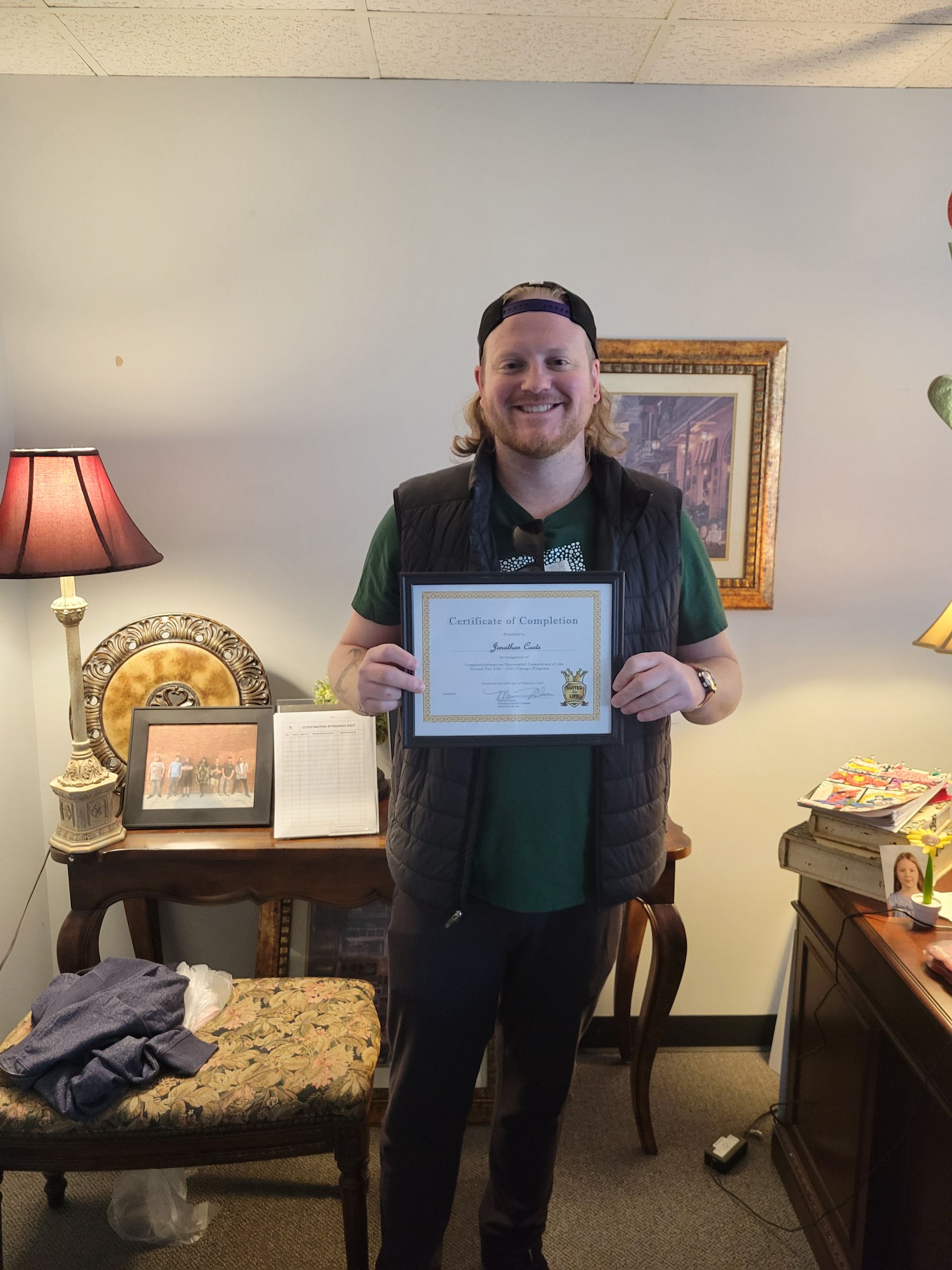 A man is holding a certificate in a living room.