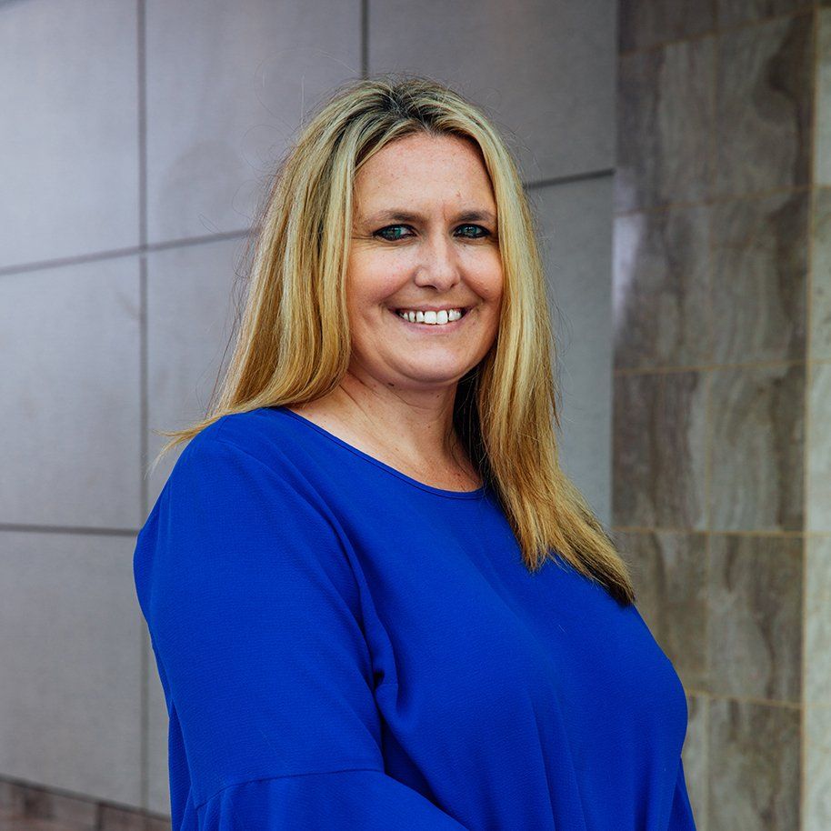 blonde woman in blue shirt smiling at camera