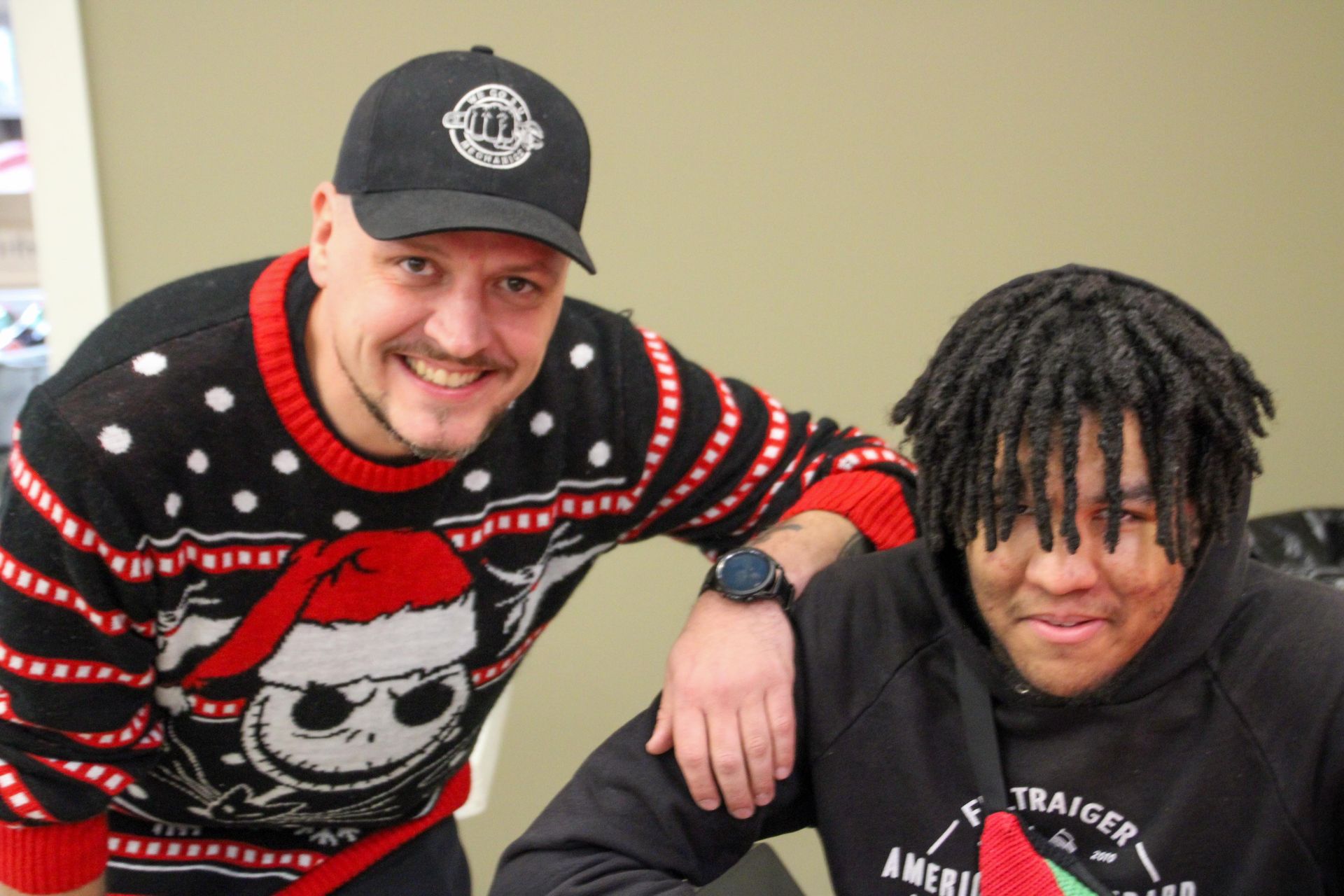 A man and a boy are posing for a picture . the boy is wearing a nightmare before christmas sweater.