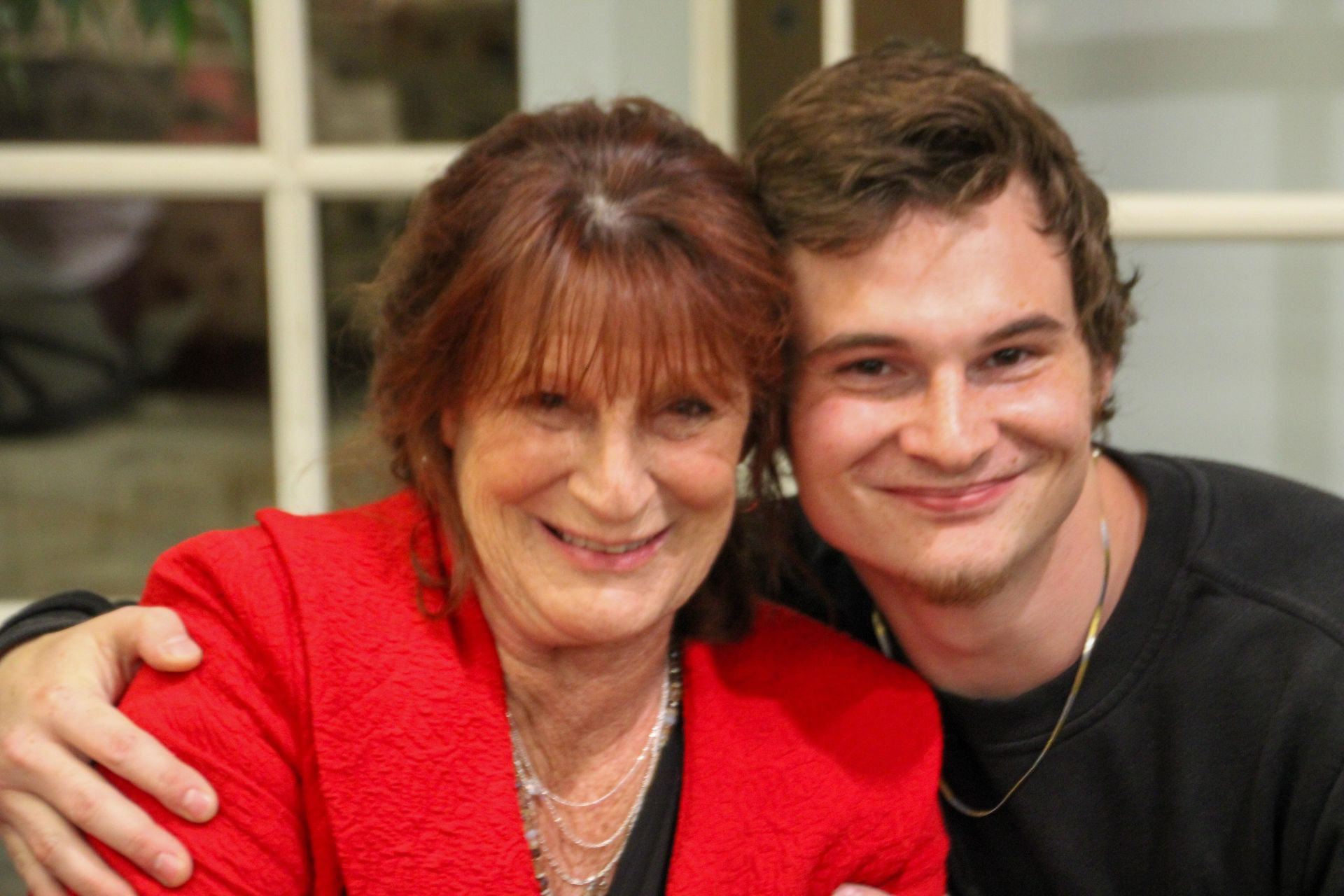 A man and a woman are posing for a picture. the woman is wearing a red jacket.