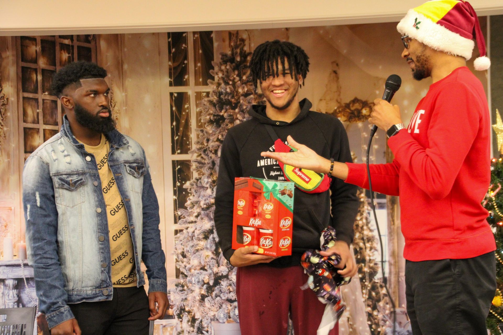 A man in a santa hat is giving a gift to another man.