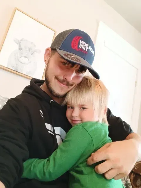 A man wearing a hat that says high day is holding a child