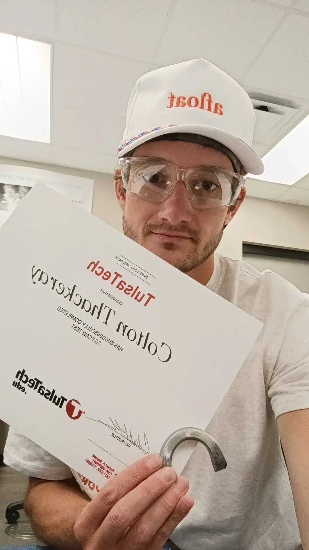 white man in ballcap and safety glasses holding up a certificate.