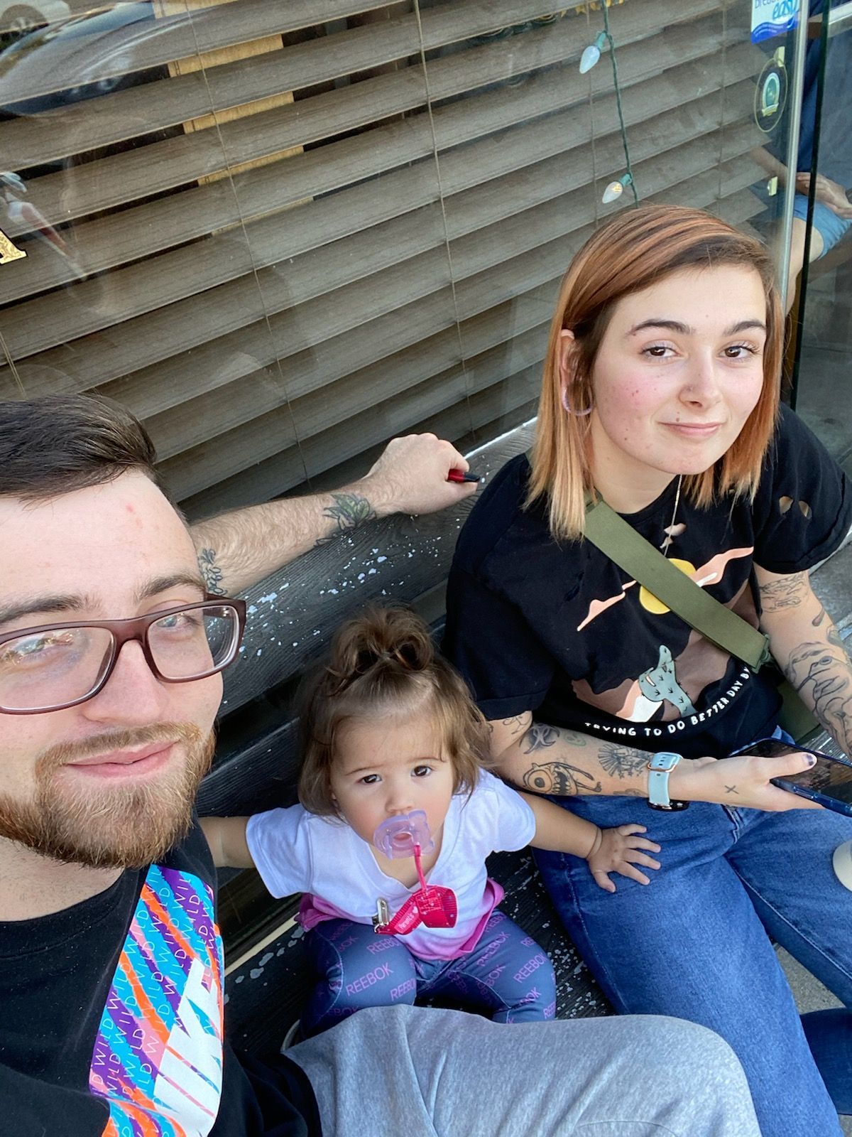 A man , woman and child are sitting on a bench.