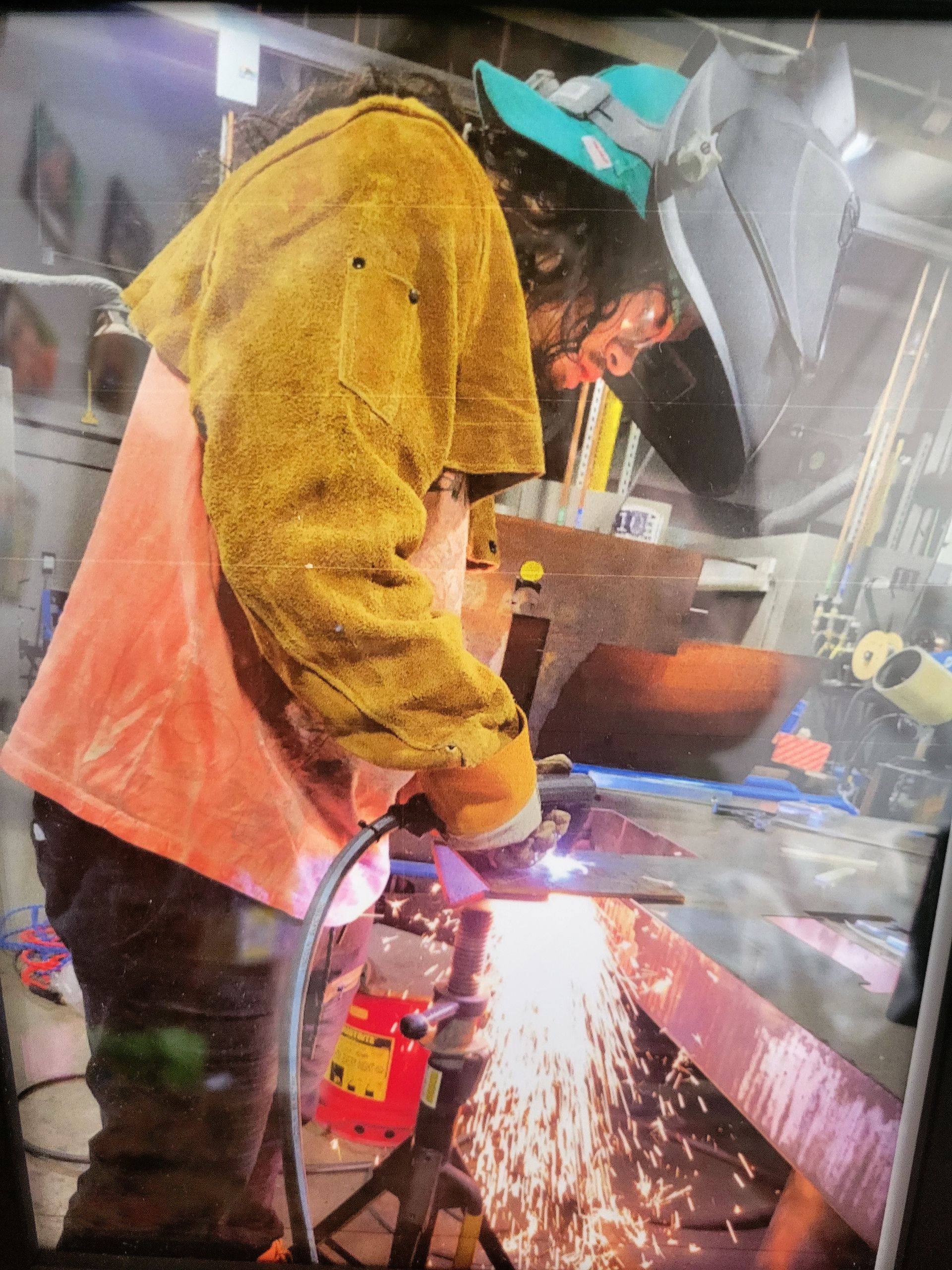 A man is welding a piece of metal in a factory.
