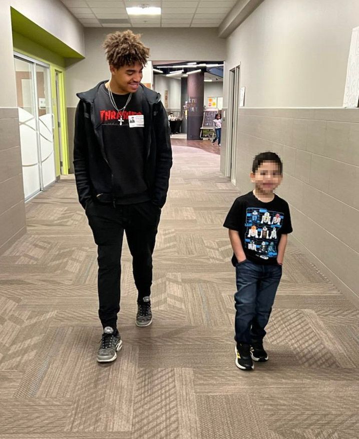 A man and a boy are walking down a hallway.