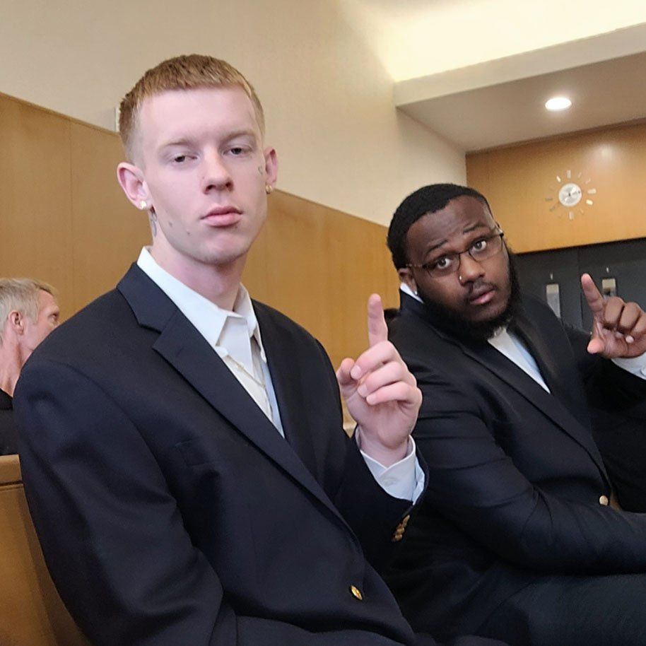 Two men in suits are sitting next to each other