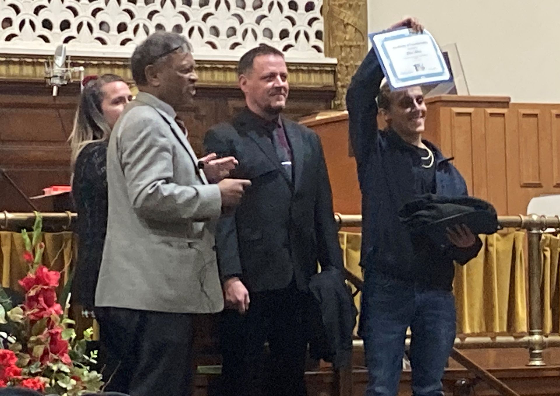 A group of people are standing in a room and one of them is holding a certificate.