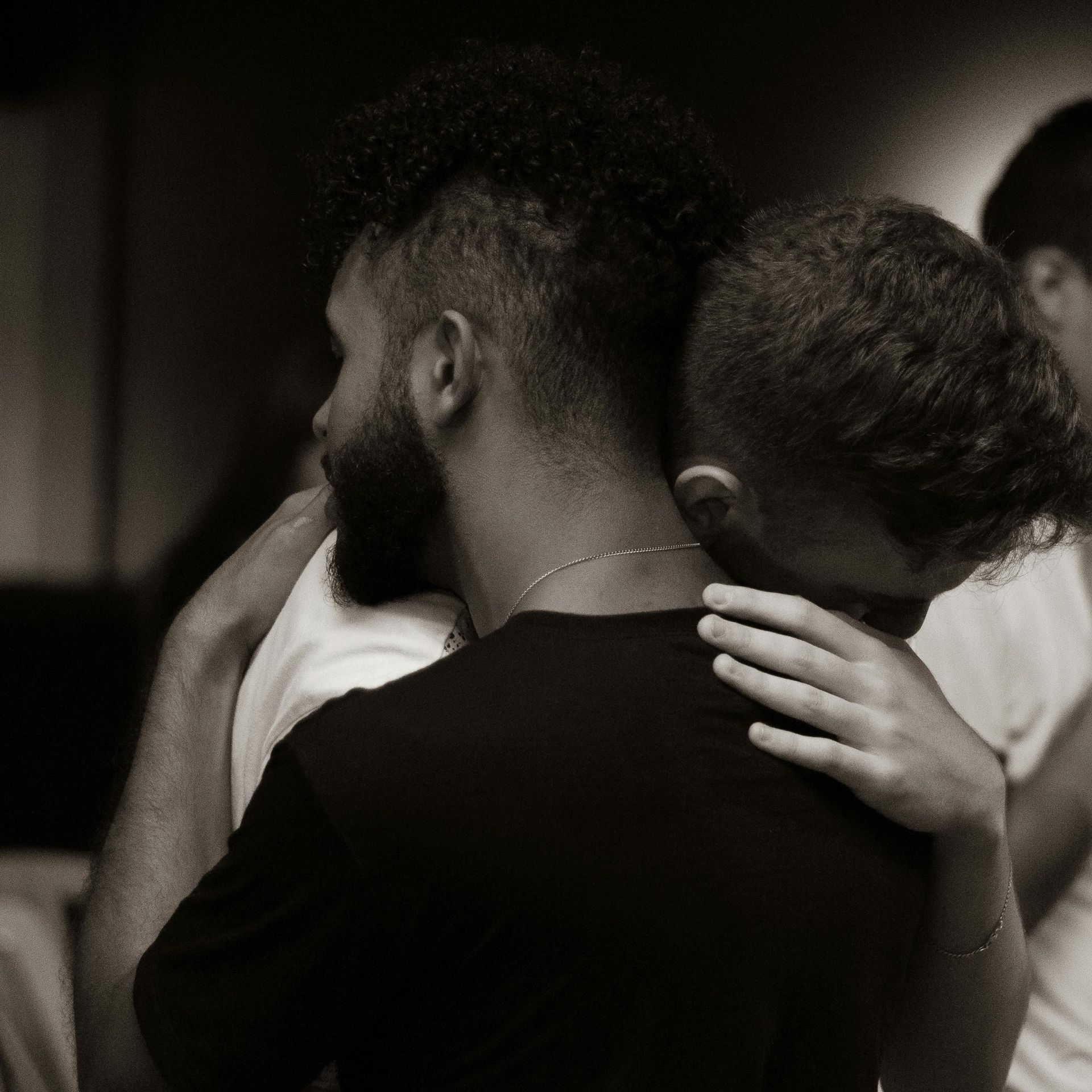 Men hugging each other in a black and white photo.