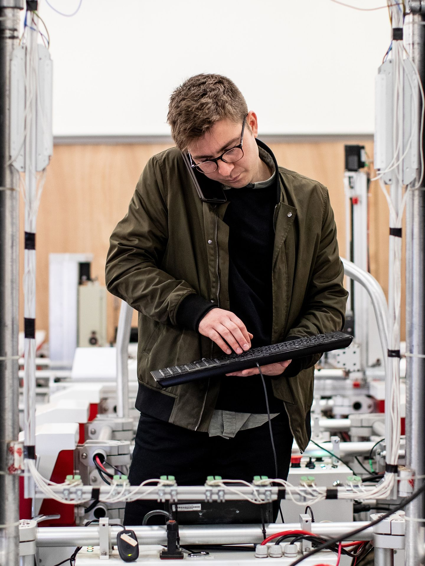 Person using a keyboard in a lab with machinery and cables, focused on adjusting equipment
