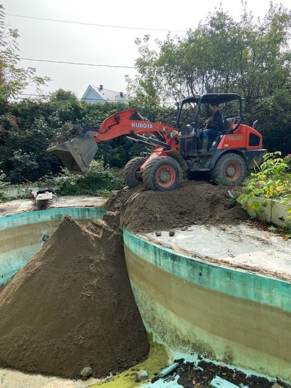 A bulldozer is moving dirt around a pool.