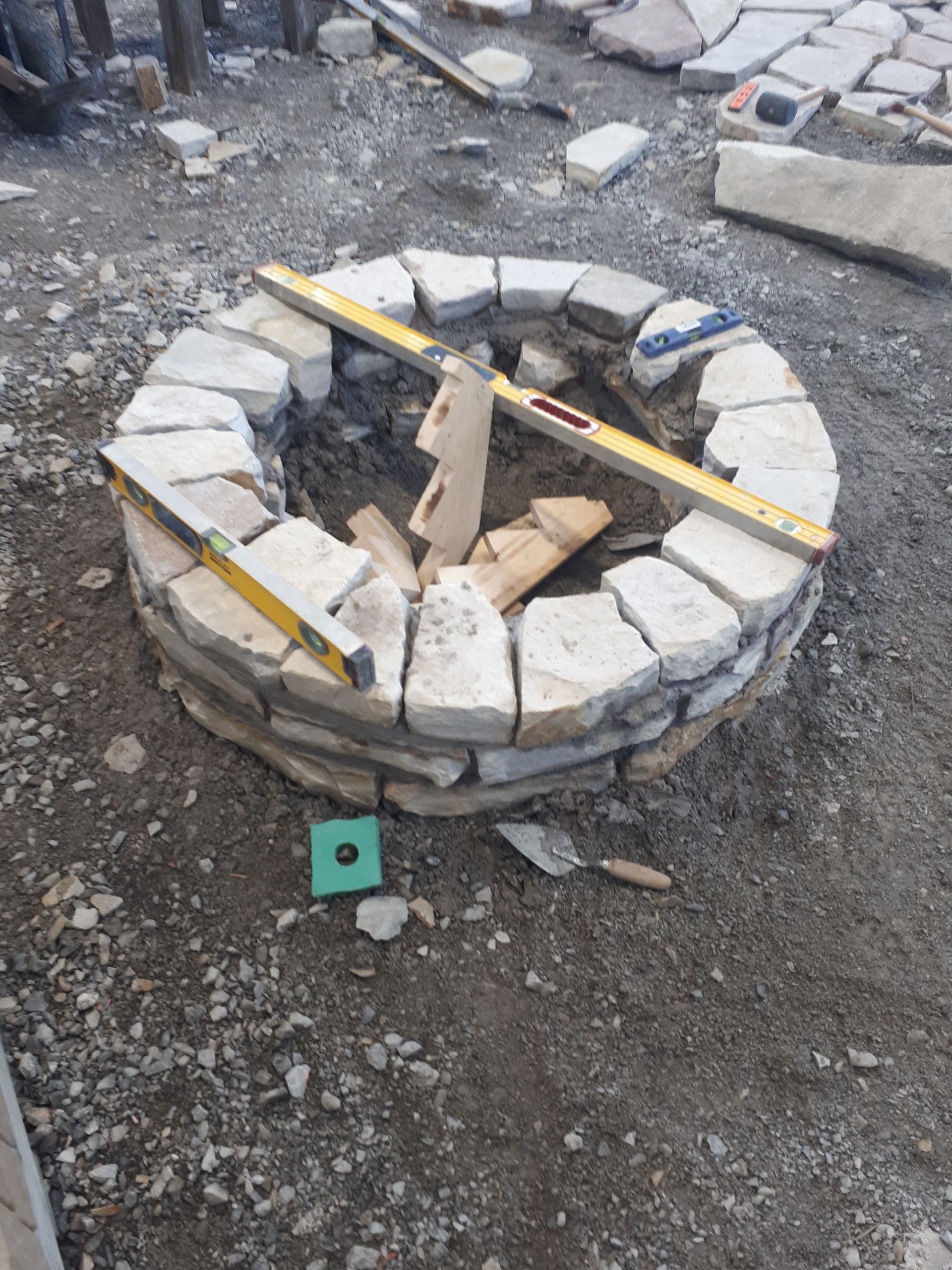 A fire pit is being built with a level on top of it