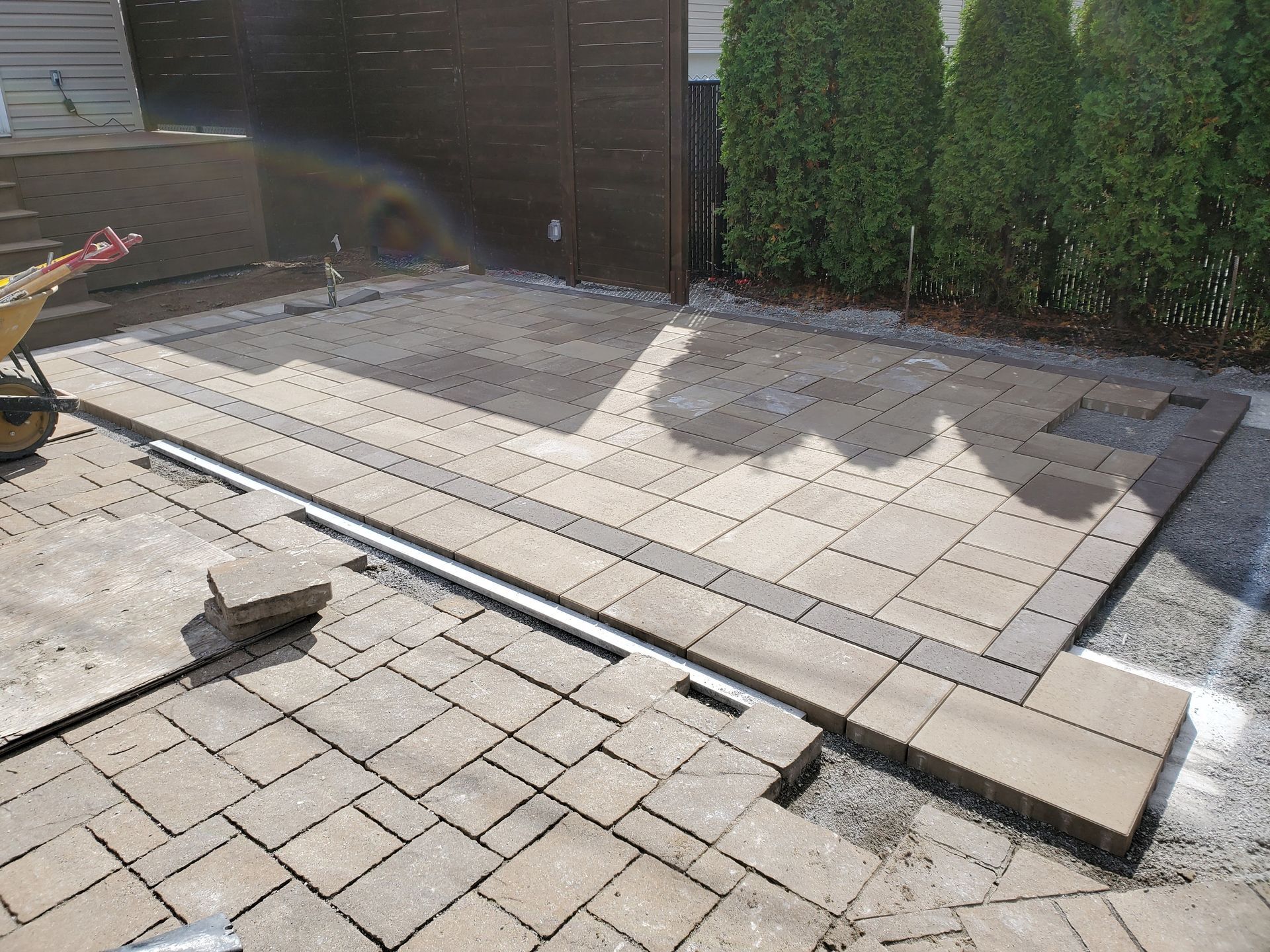 A brick walkway is being built in a backyard.