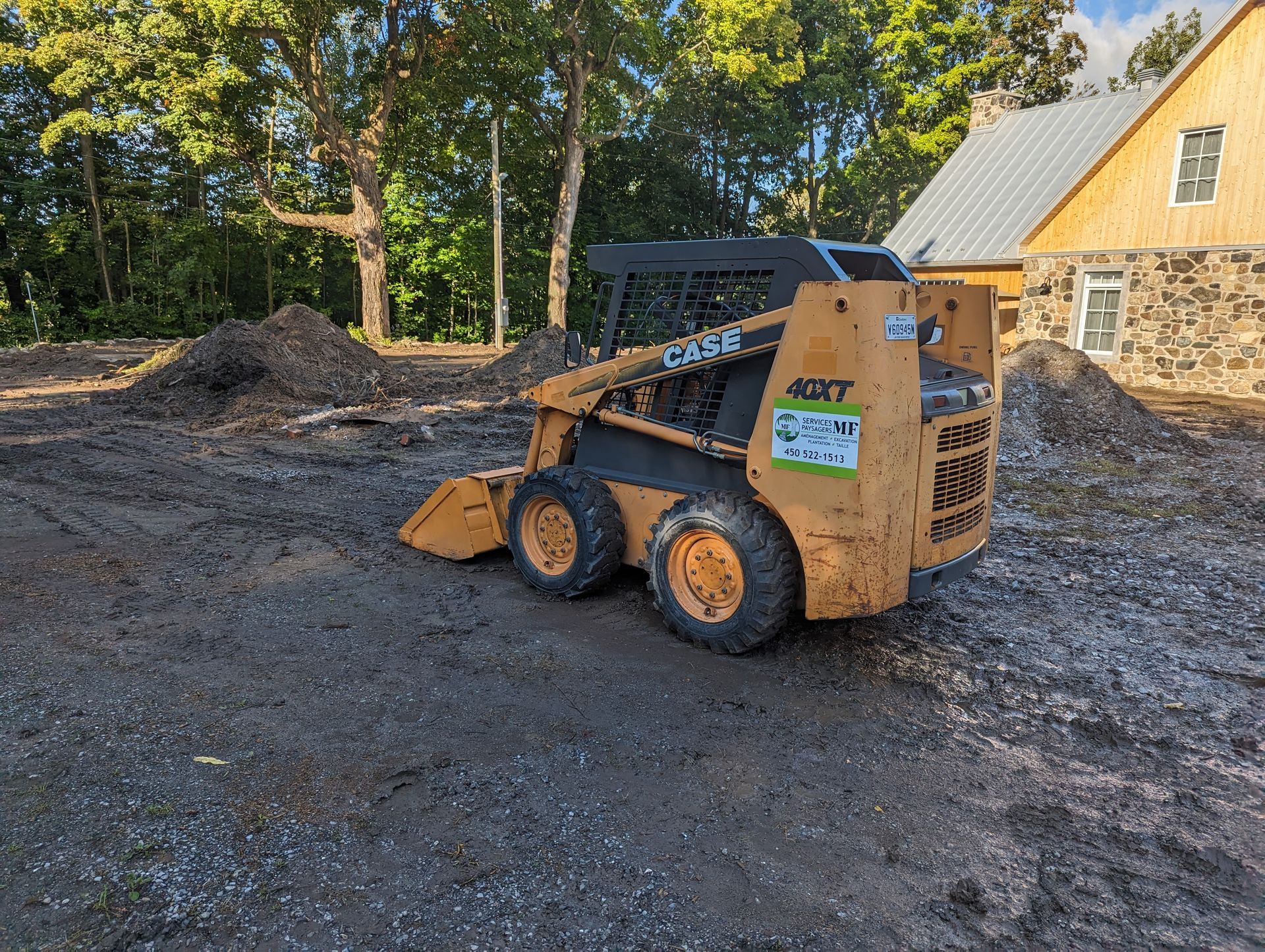 A small bulldozer is parked in a dirt lot in front of a house.