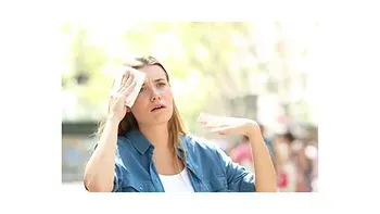 A woman is wiping her forehead with a towel.