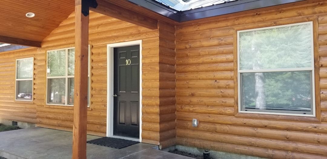 The front of a log cabin with a black door and windows.