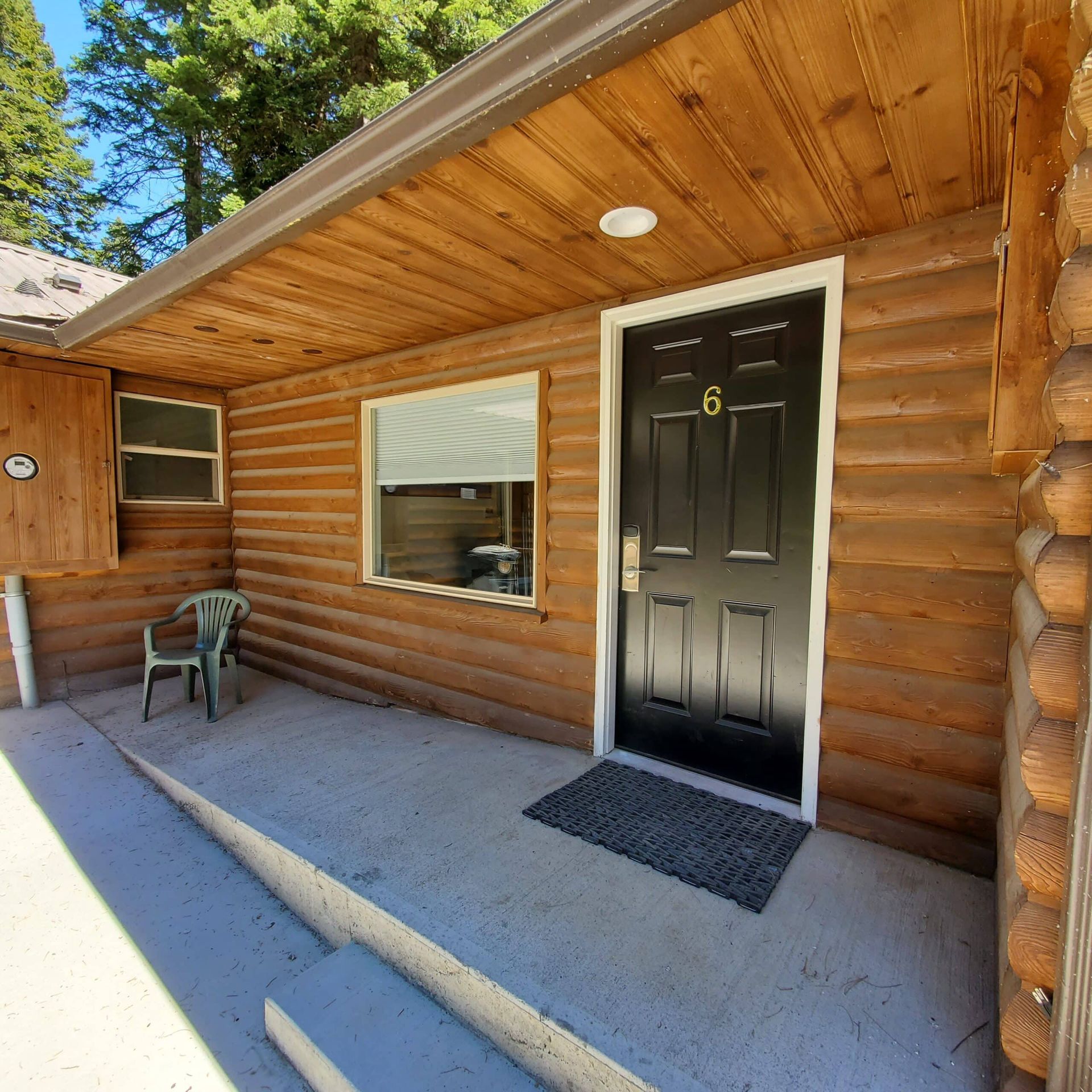 A log cabin has a black door with the number 6 on it
